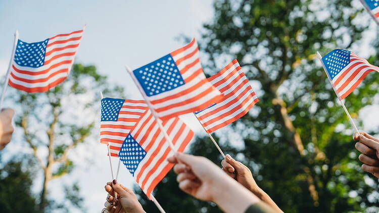 Low-angle shot of several hands waving small American flags in the air Low-angle shot of several hands waving small American flags in the air