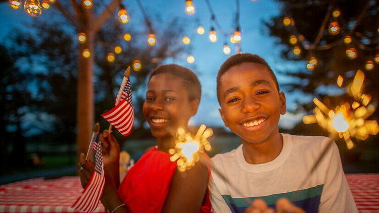 Medium close-up of two smiling children holding sparklers Medium close-up of two smiling children holding sparklers