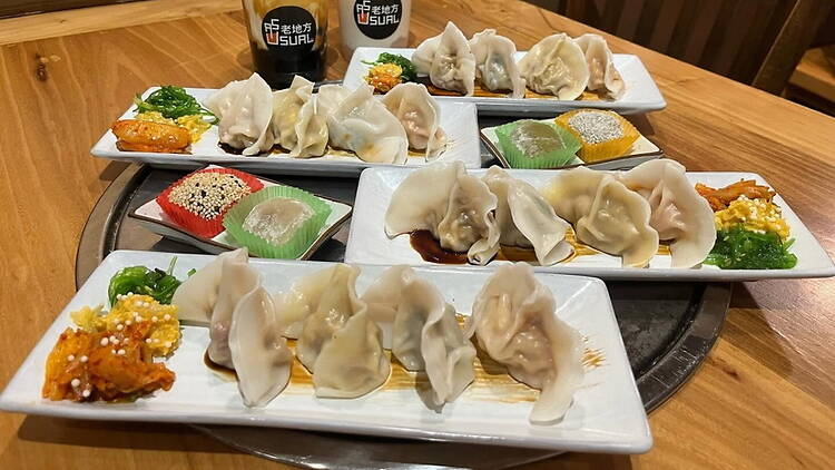 Medium close-up shot of four trays of dumplings in a wooden table Medium close-up shot of four trays of dumplings in a wooden table