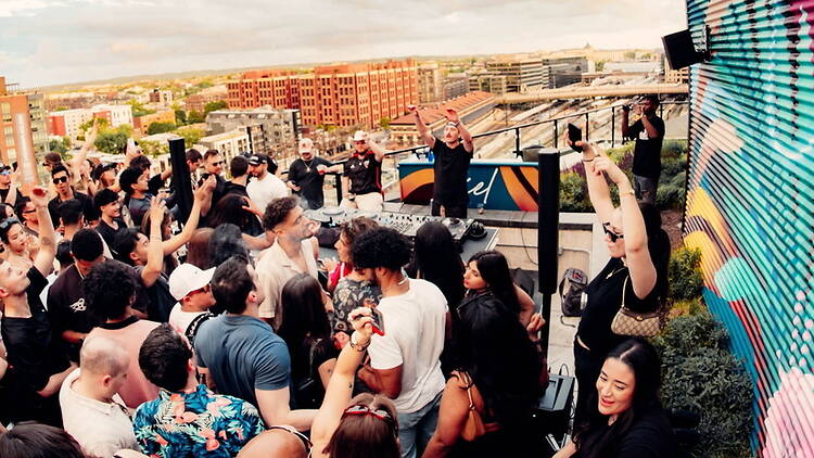 A wide shot of people partying on a rooftop. A wide shot of people partying on a rooftop.