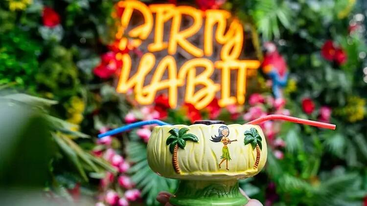 A close-up of a tropical drink with colorful straws on a tiki-themed display. A close-up of a tropical drink with colorful straws on a tiki-themed display.