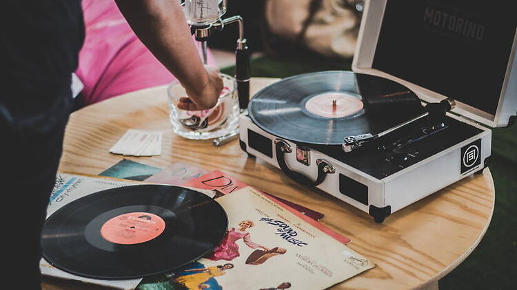 A close-up of a record player with vinyl records on a table. A close-up of a record player with vinyl records on a table.
