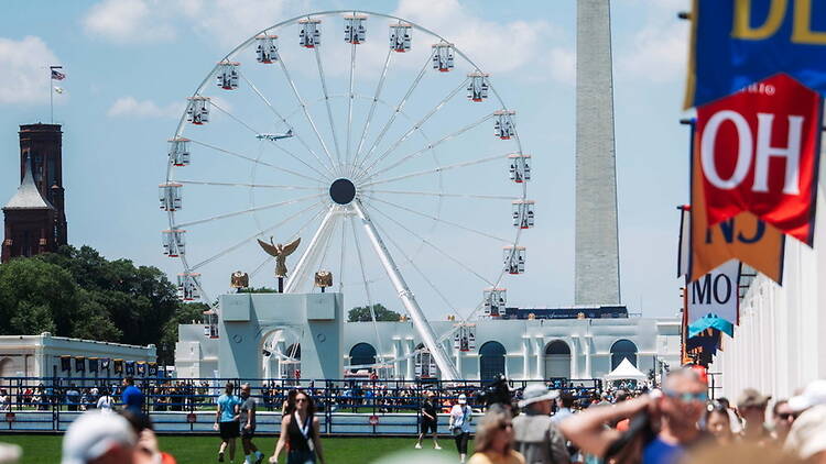 A wide shot of a Ferris wheel with people walking nearby. A wide shot of a Ferris wheel with people walking nearby.
