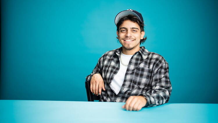 A wide shot of Ralph Barbosa sitting in a chair with his left hand on a table.
