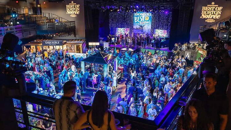 A wide shot of people gathering before a stage at an indoor event. A wide shot of people gathering before a stage at an indoor event.