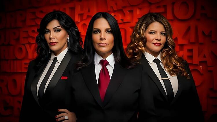 A close-up of three people posing in matching black suits.