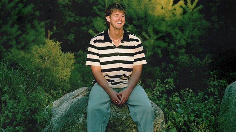 Wide shot of a person in a striped shirt sitting on a rock Wide shot of a person in a striped shirt sitting on a rock