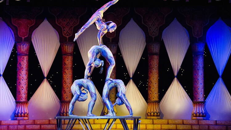 A wide shot of acrobats performing a balancing act on stage. A wide shot of acrobats performing a balancing act on stage.
