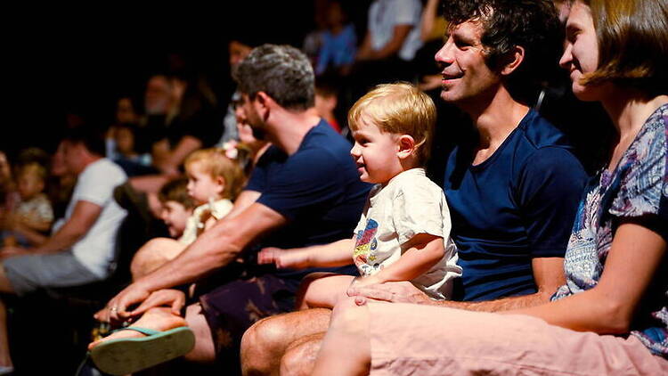 Medium close-up of of a family with a toddler sitting and watching a performance Medium close-up of of a family with a toddler sitting and watching a performance