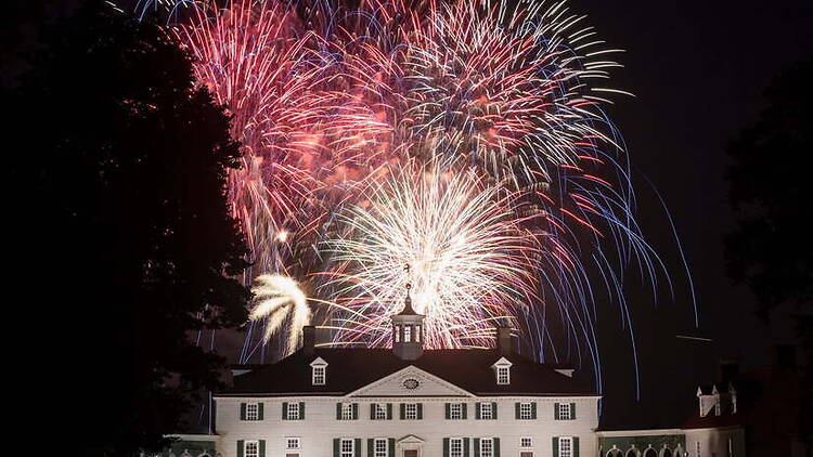 A wide shot of fireworks lighting up the sky above a historic building at night A wide shot of fireworks lighting up the sky above a historic building at night