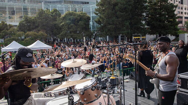 Wide shot of a band performing on an outdoor stage in front of a crowd Wide shot of a band performing on an outdoor stage in front of a crowd