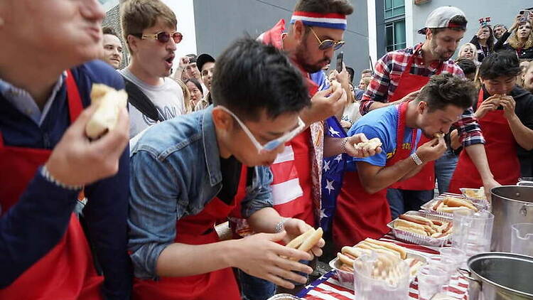 Wide shot of a group of men eating hotdogs Wide shot of a group of men eating hotdogs