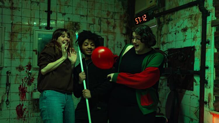 Rush Escape Game Three scared people in a creepy bathroom with blood splatters