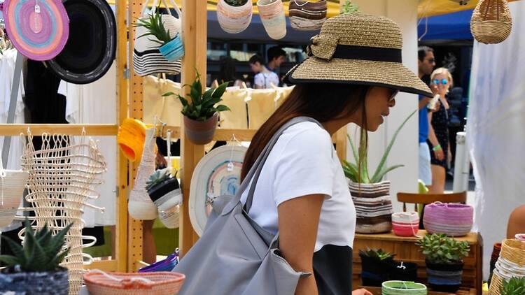 A close-up of a person browsing handmade baskets and plants at an outdoor market A close-up of a person browsing handmade baskets and plants at an outdoor market