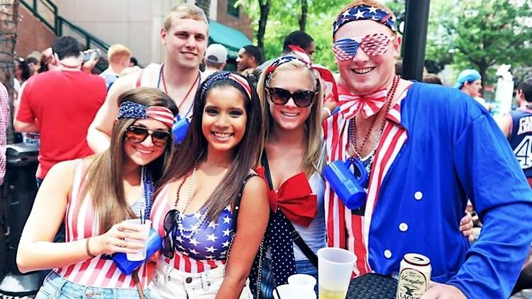 A close-up of people wearing patriotic outfits and posing together outdoors A close-up of people wearing patriotic outfits and posing together outdoors