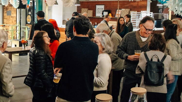 A wide shot of people chatting and holding drinks indoors A wide shot of people chatting and holding drinks indoors