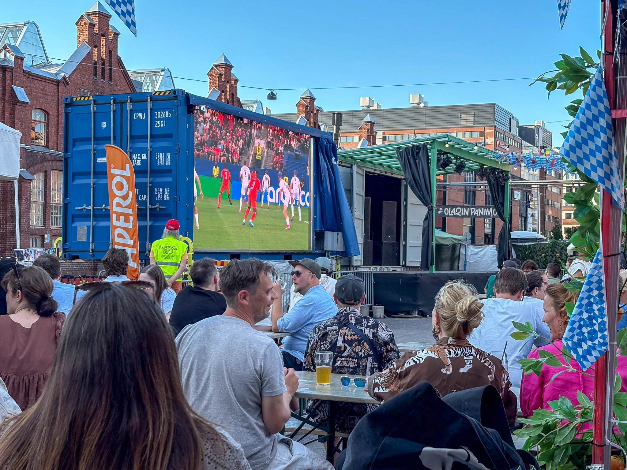 Ihmiset katsovat jalkapalloa Beergarten-terassilla Konepajan alueella Helsingiss&auml;