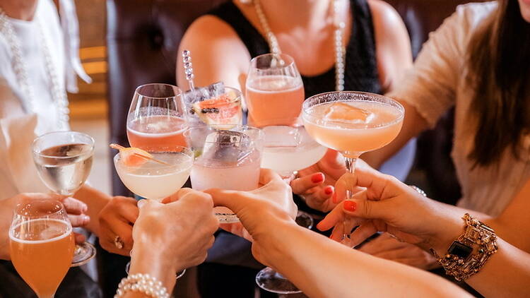 Close-up of people raising cocktail glasses in a toast. Close-up of people raising cocktail glasses in a toast.