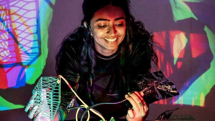 Medium shot of a person smiling while interacting with a colorful light installation. Medium shot of a person smiling while interacting with a colorful light installation.