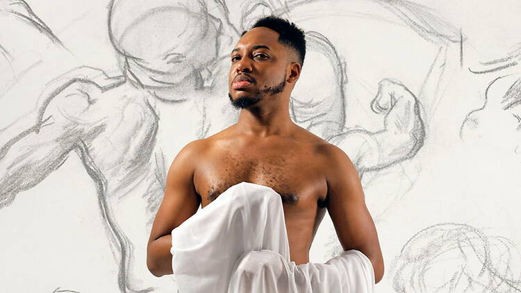 Medium shot of a person posing with a white draped cloth against a wall with figure sketches. Medium shot of a person posing with a white draped cloth against a wall with figure sketches.