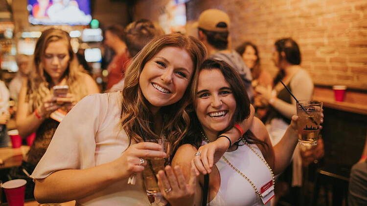 Medium close-up view of two women smiling and holding drinks. Medium close-up view of two women smiling and holding drinks.