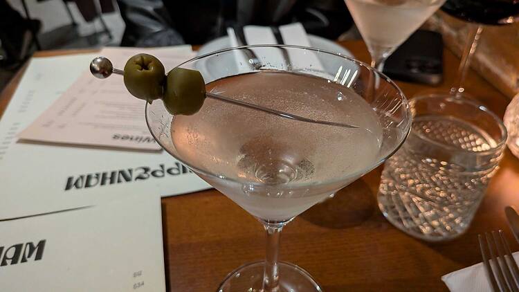 a martini with 2 olives on a table