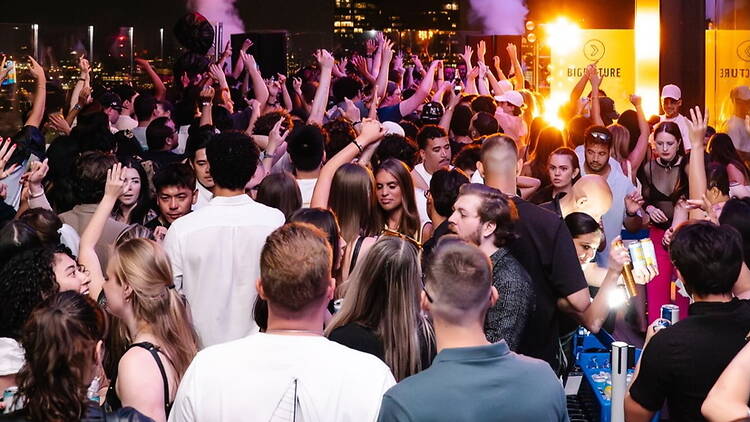Wide shot view of a crowd dancing at a nighttime outdoor party. Wide shot view of a crowd dancing at a nighttime outdoor party.