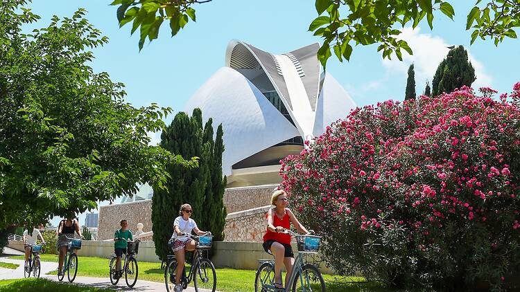 Tourists cycle past modern art building in Valencia, Spain Tourists cycle past modern art building in Valencia, Spain