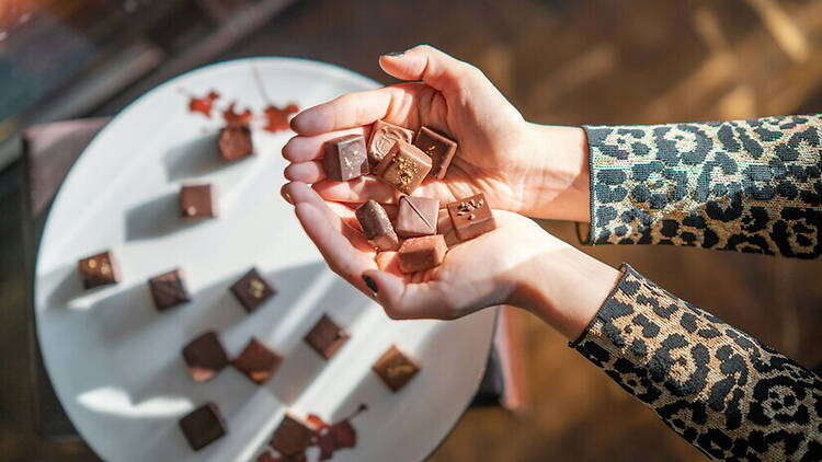 Close-up view of hands holding chocolates over a table. Close-up view of hands holding chocolates over a table.