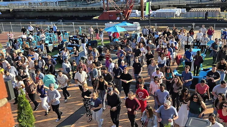 A wide shot of people dancing at an outdoor dance event A wide shot of people dancing at an outdoor dance event