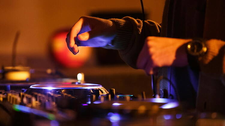 A close-up of hands adjusting DJ controls on a mixing console. A close-up of hands adjusting DJ controls on a mixing console.