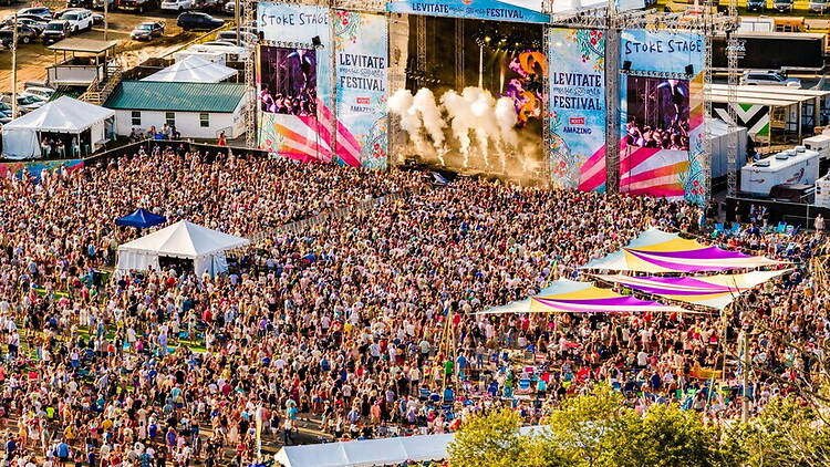 A wide shot of a crowd watching a performance at an outdoor music festival. A wide shot of a crowd watching a performance at an outdoor music festival.