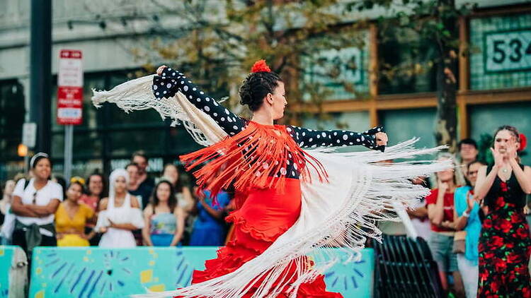 A wide shot of a dancer performing in front of a crowd at an outdoor event. A wide shot of a dancer performing in front of a crowd at an outdoor event.