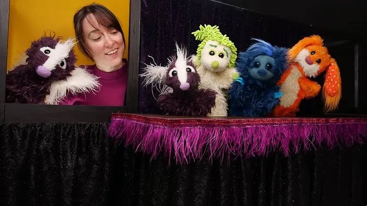 A wide shot of a puppeteer performing with colorful hand puppets on a puppet stage. A wide shot of a puppeteer performing with colorful hand puppets on a puppet stage.