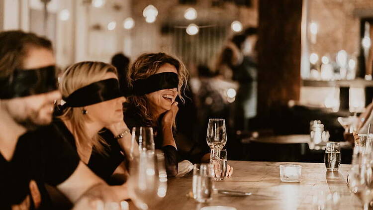 Wide shot view of blindfolded people in a table. Wide shot view of blindfolded people in a table.