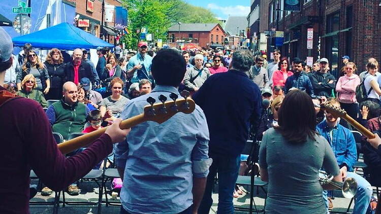 Wide shot view of a band playing in a street in front of large audience. Wide shot view of a band playing in a street in front of large audience.