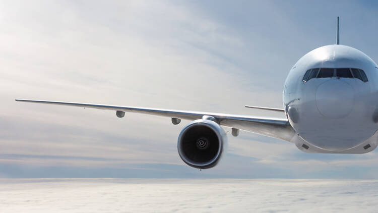 Front view of the white wide body passenger airplane flies in the air above the clouds Front view of the white wide body passenger airplane flies in the air above the clouds