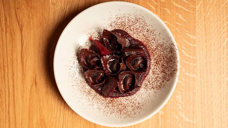 A white plate of purple Beetroot, goat's curd and cocoa tortellini at Margo