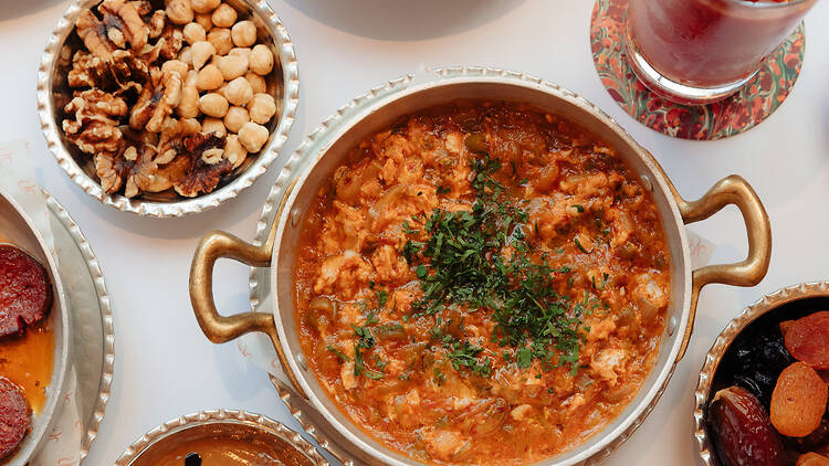 A plate of Turkish food surrounded by bowls of nuts and dates 
