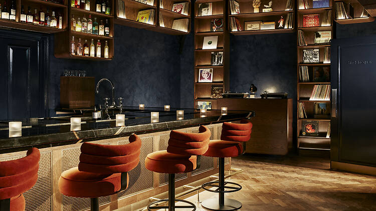 4 bar stools surrounded by shelves displaying records and more