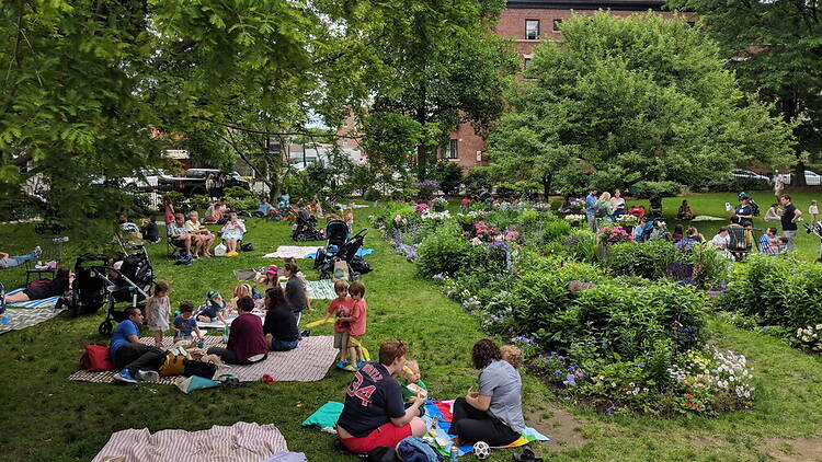 A wide shot of families relaxing and picnicking in a flower garden at a city park. A wide shot of families relaxing and picnicking in a flower garden at a city park.