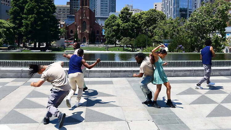 A wide shot of dancers performing in a city park plaza. A wide shot of dancers performing in a city park plaza.