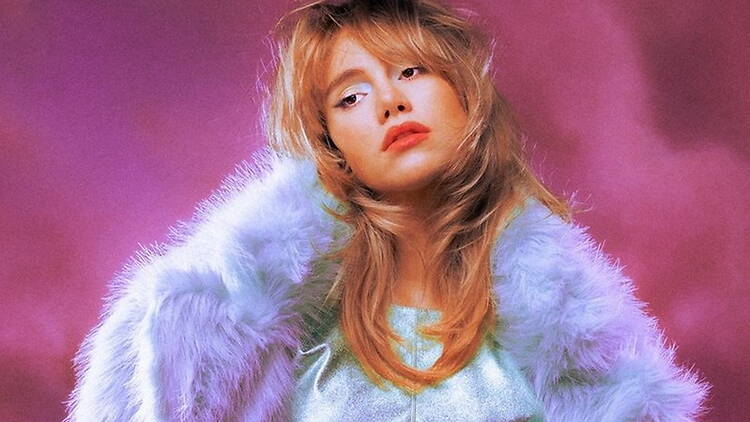 Close-up of a person posing against a pink studio background.