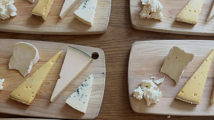 A wide shot of assorted cheeses arranged on wooden boards for tasting. A wide shot of assorted cheeses arranged on wooden boards for tasting.