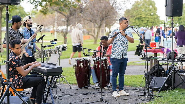 A wide shot of a band performing in a park. A wide shot of a band performing in a park.