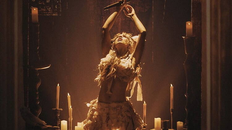 A wide shot of a singer performing on a candlelit stage. A wide shot of a singer performing on a candlelit stage.