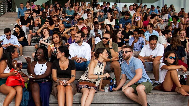 A wide shot of people sitting and socializing on outdoor steps. A wide shot of people sitting and socializing on outdoor steps.