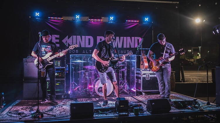 A wide shot of a band performing on a stage under concert lights. A wide shot of a band performing on a stage under concert lights.