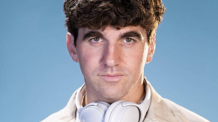 Close-up of a person wearing headphones looking at the camera against a blue background. Close-up of a person wearing headphones looking at the camera against a blue background.