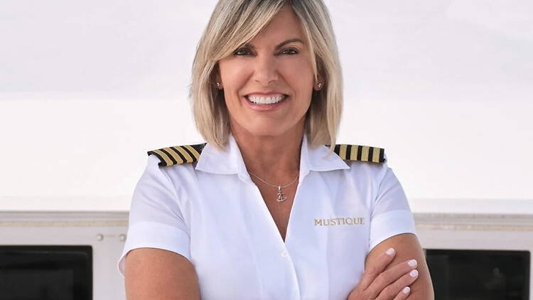 Close-up of a person smiling with arms crossed in a captain's uniform aboard a yacht. Close-up of a person smiling with arms crossed in a captain's uniform aboard a yacht.